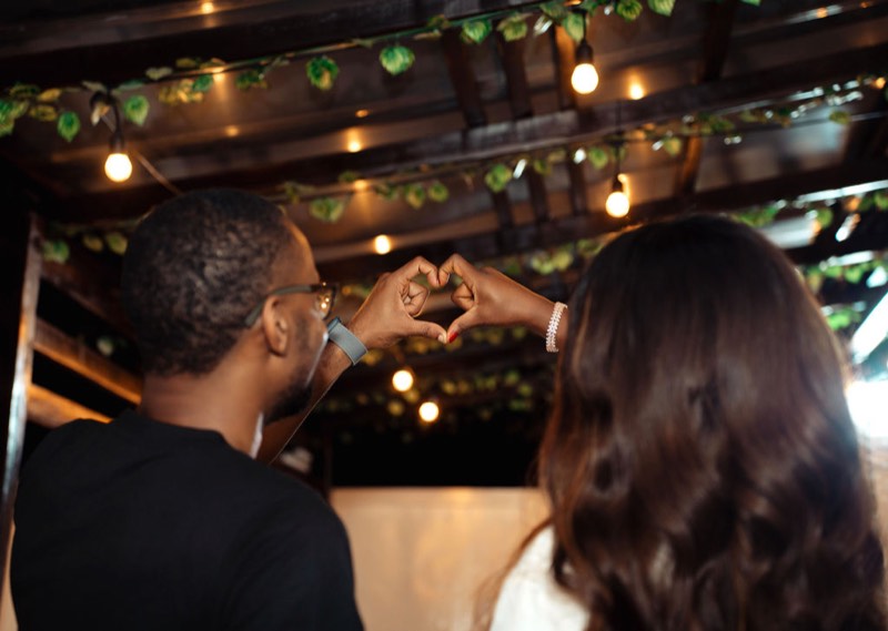 The couple under warm string lights at dusk